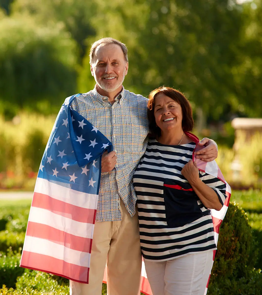 Man and woman standing outdoors with an American flag draped over them