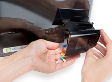 Hand turning MedaCube dispense drawer and pouring medications into another hand. 